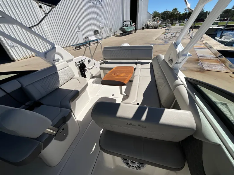 Slide: The Image of Interior of a 2021 Sea Ray SDX 250 Outboard with gray upholstery and a wooden table. - 33