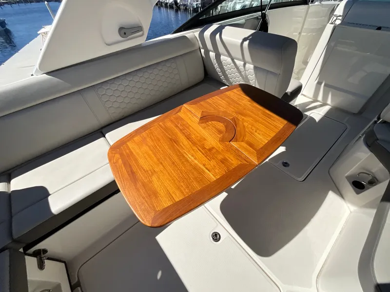 Slide: The Image of A sleek wooden table in a modern boat with gray upholstery and an open canopy. - 31