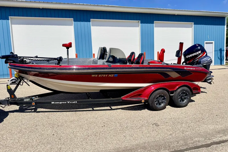 Slide: The Image of 2009 Ranger 620VS Fisherman boat with Evinrude motor, parked on trailer near blue building. - 1