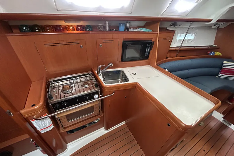 Slide: The Image of Interior of a 2009 Beneteau 343 yacht featuring a compact kitchen with stove and sink. - 24