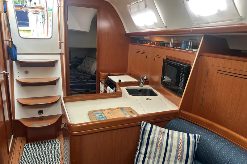 Slide: The Image of Interior of 2009 Beneteau 343 sailboat with kitchen, sink, microwave, and cozy seating area. - 18