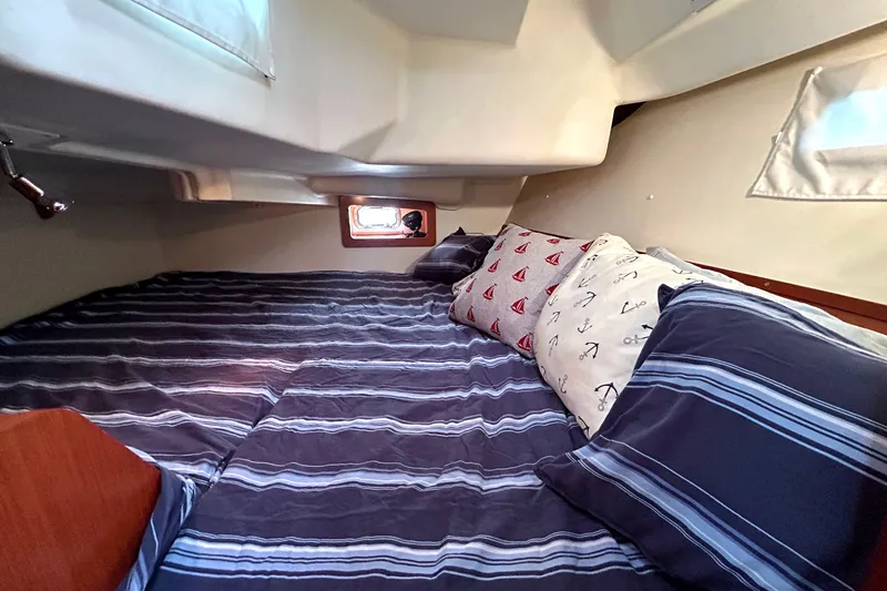 Slide: The Image of Cozy cabin interior of 2009 Beneteau 343 sailboat with striped bedding and nautical-themed pillows. - 29