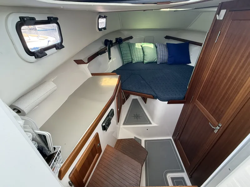 Slide: The Image of The cabin of the 2020 NorthCoast 285 HT features a cozy bed, wooden doors, and windows. - 22