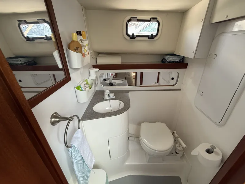 Slide: The Image of The image shows a clean boat bathroom with a sink, toilet, and mirror. - 27
