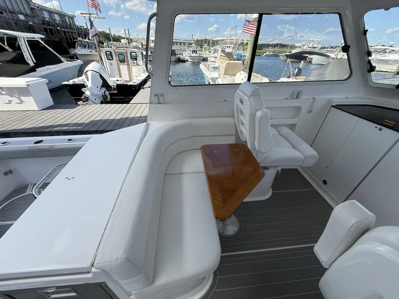 Slide: The Image of Interior of a boat with white seating and a wooden table, docked at a marina. - 15