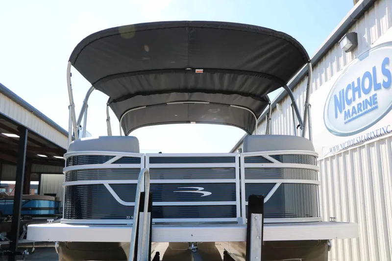 Slide: The Image of A 2027 Bennington 22 SSR Tri Toon with a black canopy, parked at Nichols Marine. - 8