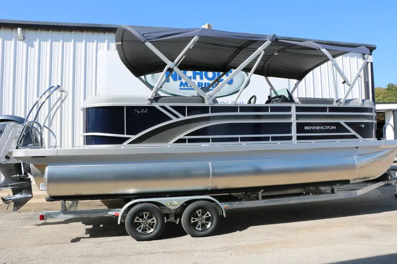 Slide: The Image of A 2027 Bennington 22 SSR Tri Toon on a trailer in front of a building. - 13