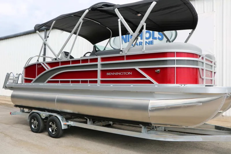 Slide: The Image of A 2027 Bennington 22 SSB Tri Toon on a trailer. It features a red and silver design. - 4