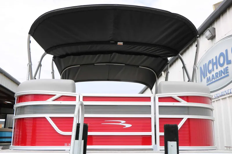 Slide: The Image of A red 2027 Bennington 22 SSB Tri Toon with a black canopy, parked beside a building. - 7