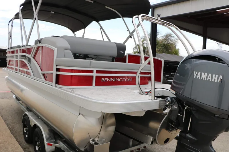 Slide: The Image of A 2027 Bennington 22 SSB Tri Toon with a Yamaha engine, parked on a trailer. - 22