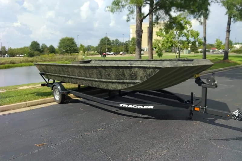 The Image of 2026 Tracker Grizzly 2072 Utility boat on trailer, parked near a pond. - 0