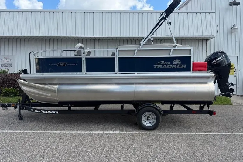 The Image of 2026 Sun Tracker Bass Buggy 16 XL Select pontoon boat on trailer, parked outdoors. - 0
