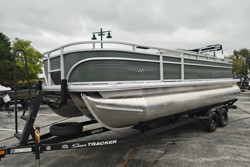 Slide: The Image of 2027 Sun Tracker Fishin' Barge 22 XP3 pontoon boat on trailer, parked outdoors. - 50