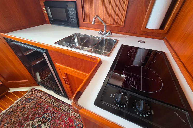 Slide: The Image of 1999 Fortier Express 33 yacht kitchen with stove, sink, microwave, and wooden cabinetry. - 24