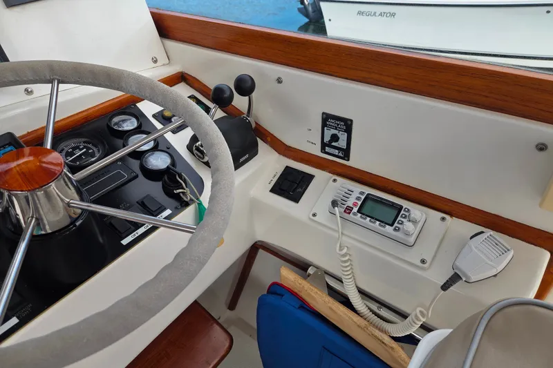 Slide: The Image of Steering wheel and controls of a 1999 Fortier Express 33 boat cockpit. - 13