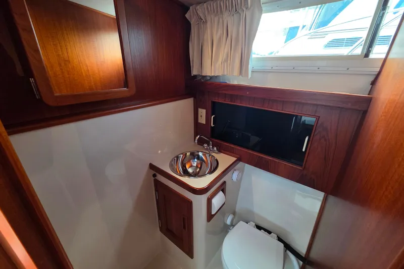 Slide: The Image of Compact bathroom in 1999 Fortier Express 33 boat with wooden cabinetry and stainless steel sink. - 25