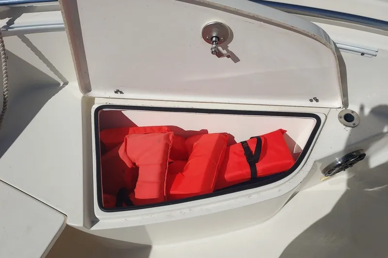 Slide: The Image of An open storage compartment on a 2018 Cobia 220 Center Console boat with red life jackets. - 11