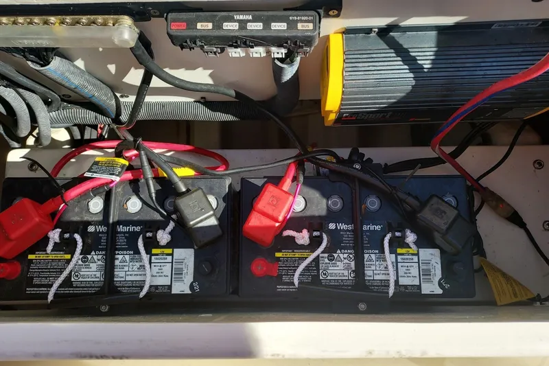 Slide: The Image of Batteries and wiring in a boat's engine compartment, with various connections and a charger. - 13