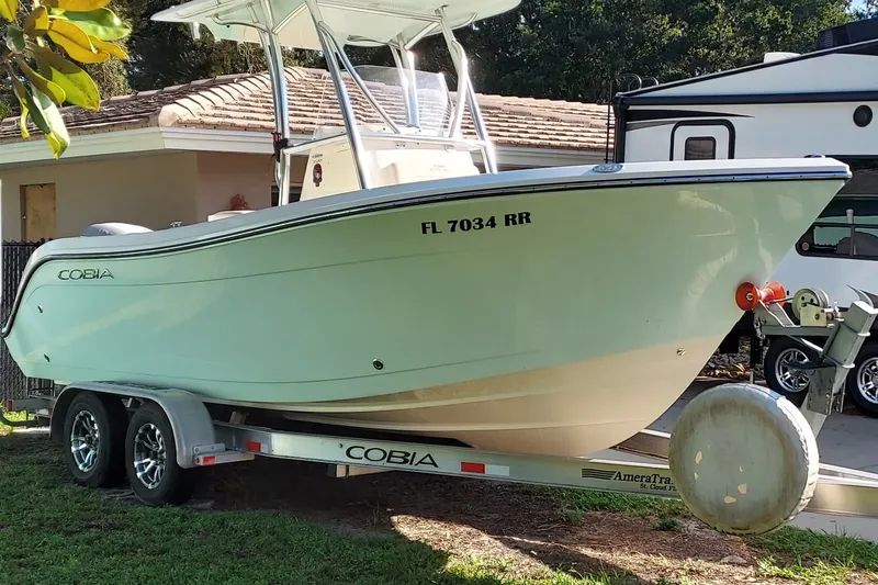 Slide: The Image of 2018 Cobia 220 Center Console boat on trailer, parked beside a house. - 4