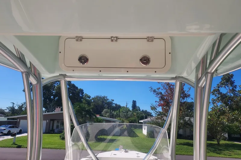 Slide: The Image of 2018 Cobia 220 Center Console boat with T-top and clear windshield, parked in residential area. - 9