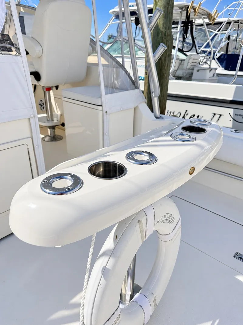 Slide: The Image of A 2005 Carolina Classic 28 Express with fishing rod holders and a life ring on the deck. - 12