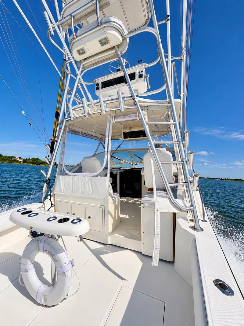 Slide: The Image of A 2005 Carolina Classic 28 Express on the water. Visible are the helm and fishing rod holders. - 10