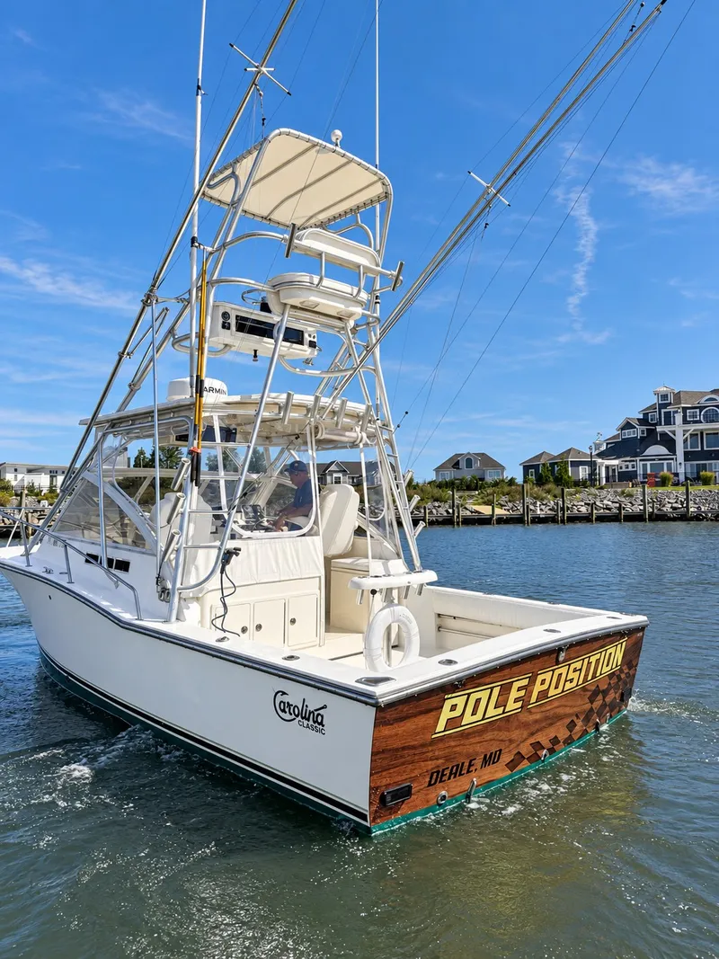 Slide: The Image of A 2005 Carolina Classic 28 Express boat on the water with fishing rods and an elevated helm. - 7