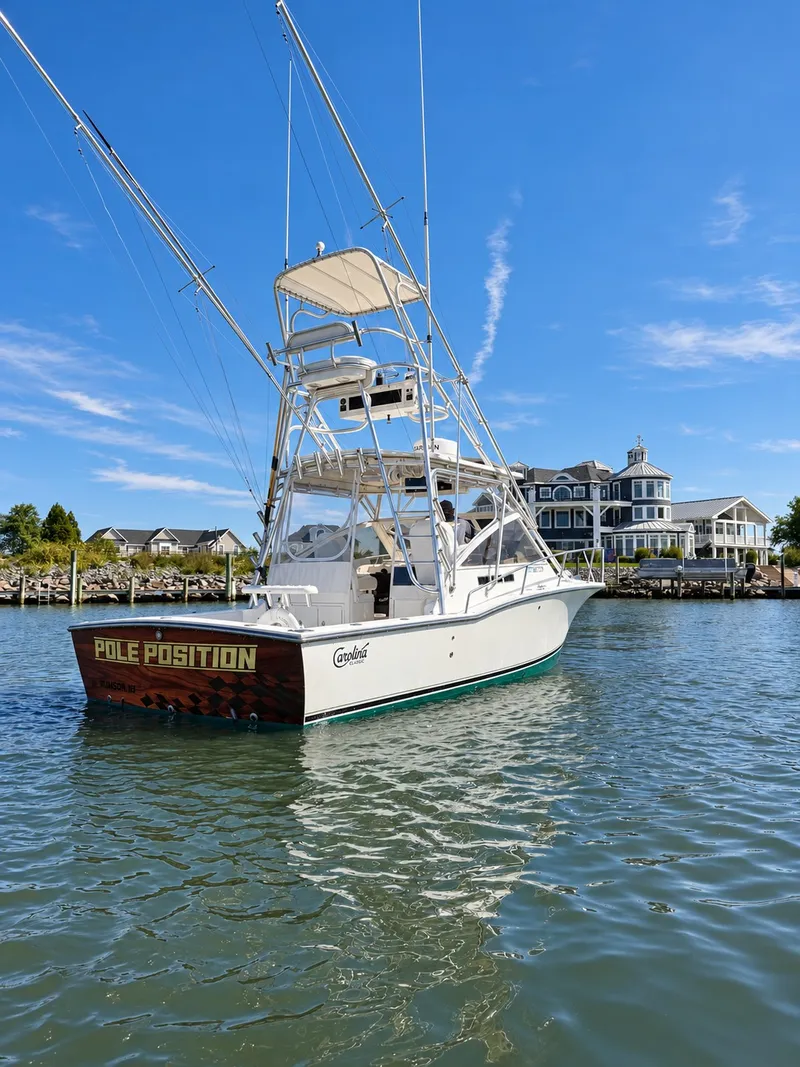 Slide: The Image of A 2005 Carolina Classic 28 Express boat on the water in front of a large house. - 6