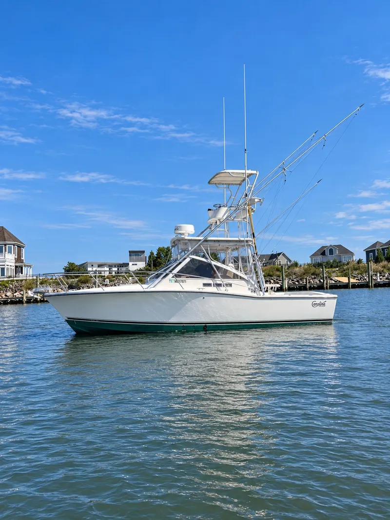 The Image of A 2005 Carolina Classic 28 Express boat on calm water with a coastal backdrop. - 3