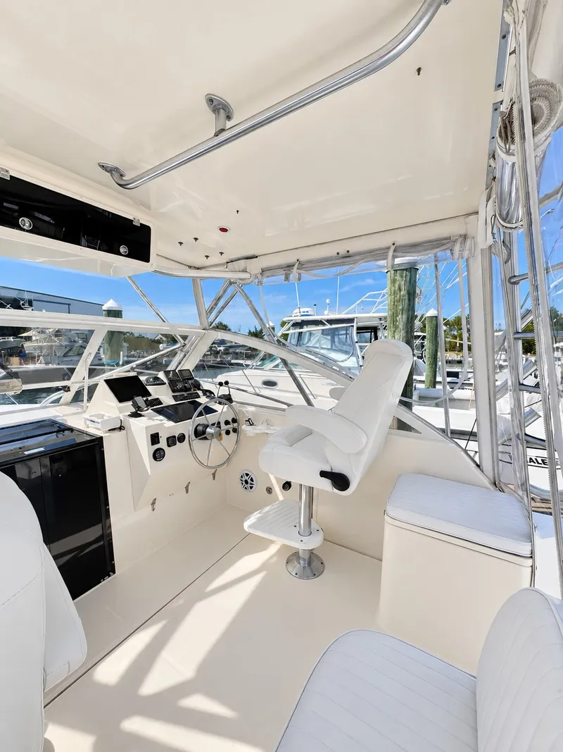 Slide: The Image of The cockpit of a 2005 Carolina Classic 28 Express with white seats and a helm console. - 15