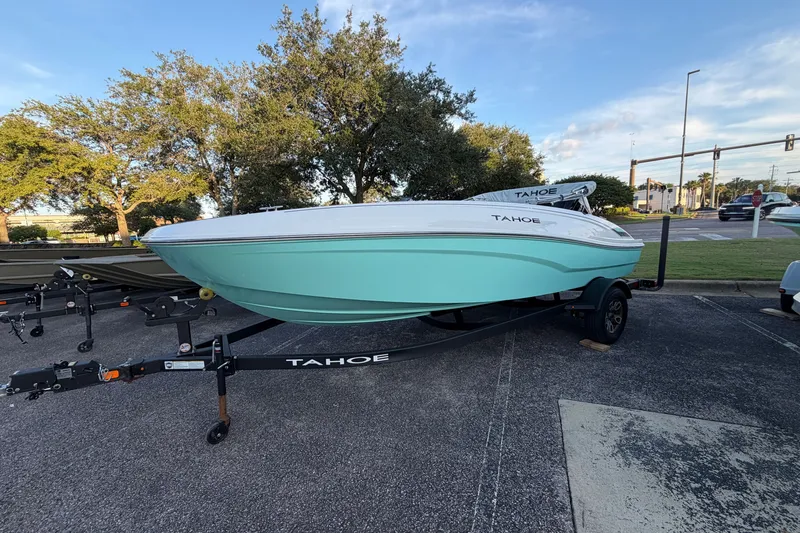 Slide: The Image of 2026 Tahoe T18 boat on trailer, parked outdoors, with trees and road in background. - 1