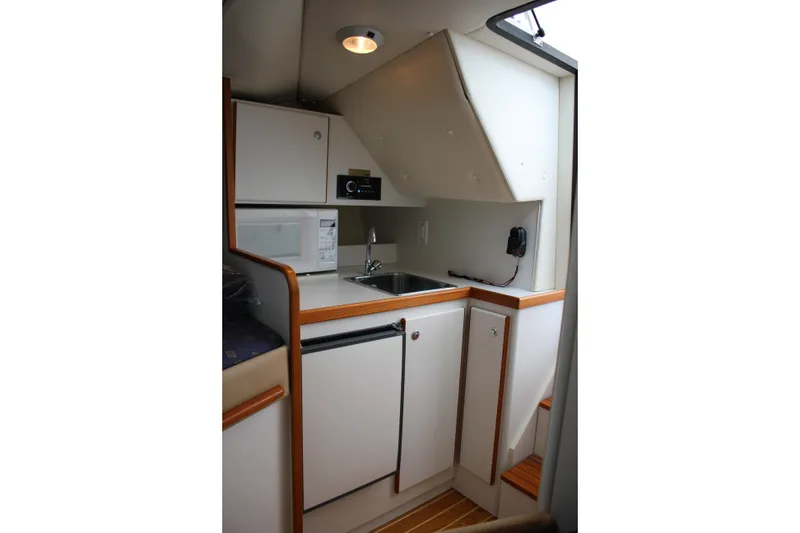 Slide: The Image of 2001 Tiara Yachts 2900 Coronet interior kitchenette with sink, microwave, and compact fridge. - 21