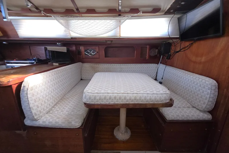 Slide: The Image of Interior of a 1970 Newport 41 sailboat with cushioned seating and wooden table. - 5