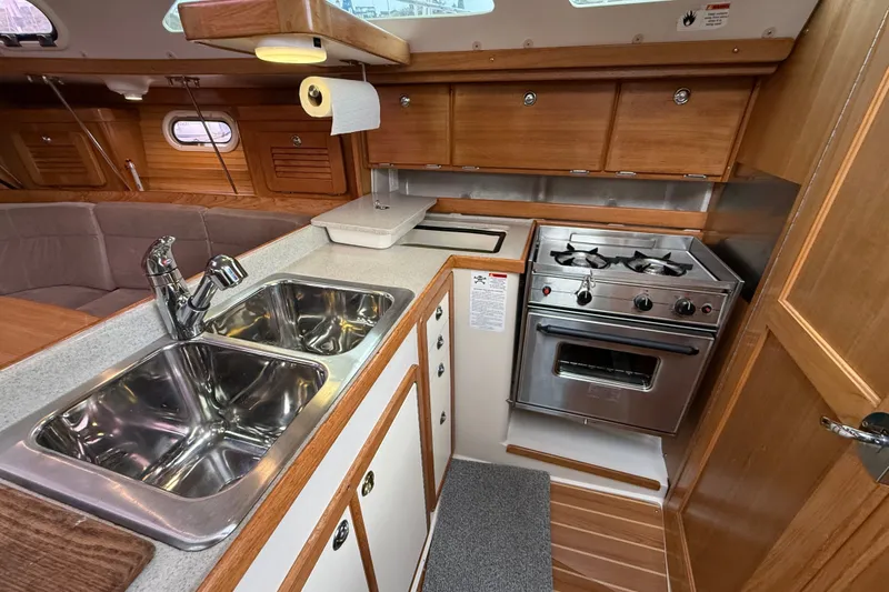 Slide: The Image of Interior of 2007 Catalina 34 MkII yacht kitchen with stove, sink, and wooden cabinetry. - 59