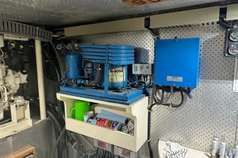 Slide: The Image of Engine room of a 1989 DeFever 54 yacht with mechanical equipment and storage shelves. - 48