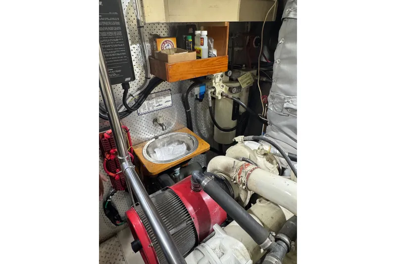 Slide: The Image of Engine room of 1989 DeFever 54 yacht with mechanical components and storage shelf. - 53