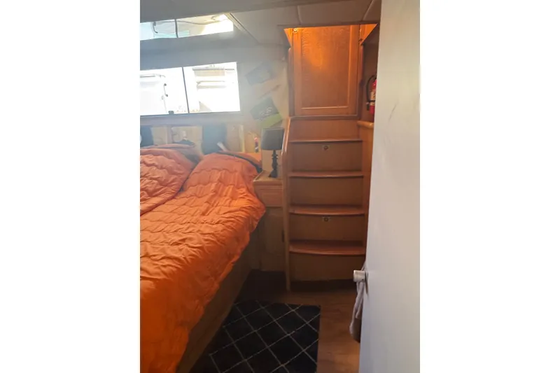 Slide: The Image of Cozy cabin interior of 1989 DeFever 54 yacht with orange bedding and wooden stairs. - 43