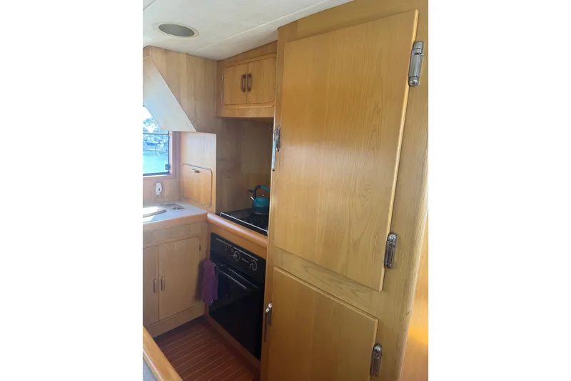 Slide: The Image of Compact kitchen in a 1989 DeFever 54 yacht with wooden cabinetry and appliances. - 17