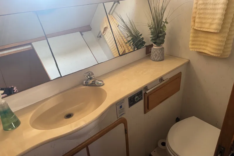 Slide: The Image of Bathroom interior of a 1989 DeFever 54 yacht, featuring a sink, mirror, and decorative plant. - 26