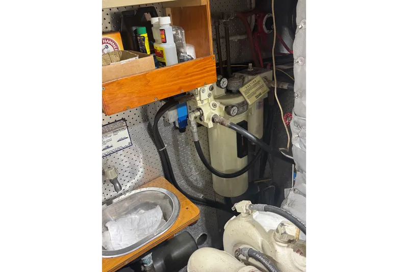 Slide: The Image of Engine room of 1989 DeFever 54 yacht with fuel filter system and storage shelf. - 56
