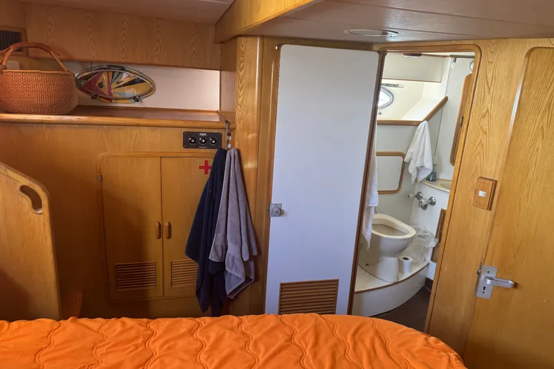 Slide: The Image of Interior of 1989 DeFever 54 yacht cabin with bathroom, wooden cabinetry, and orange bedding. - 39