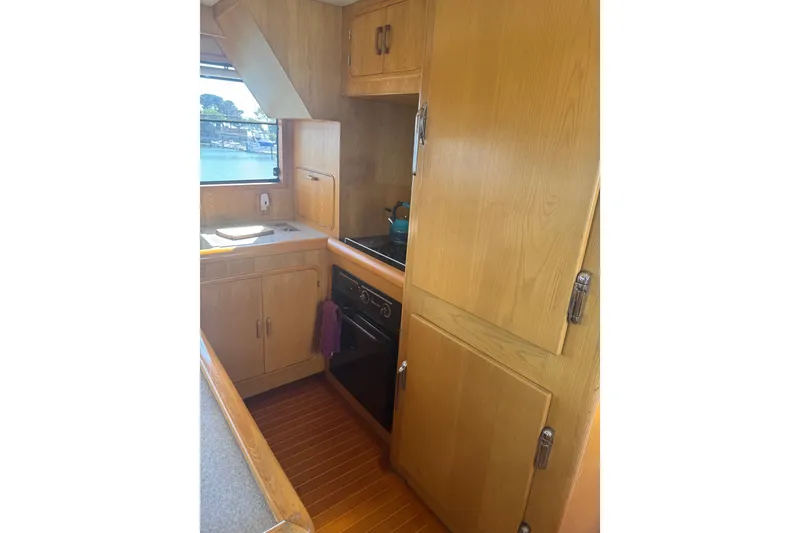 Slide: The Image of 1989 DeFever 54 yacht kitchen with wooden cabinets, stove, and window view. - 24