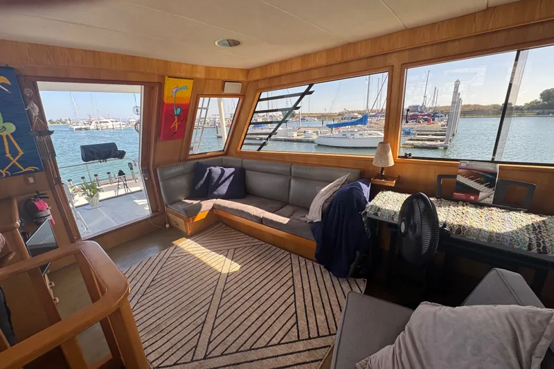Slide: The Image of Interior of 1989 DeFever 54 yacht with cozy seating, large windows, and marina view. - 52