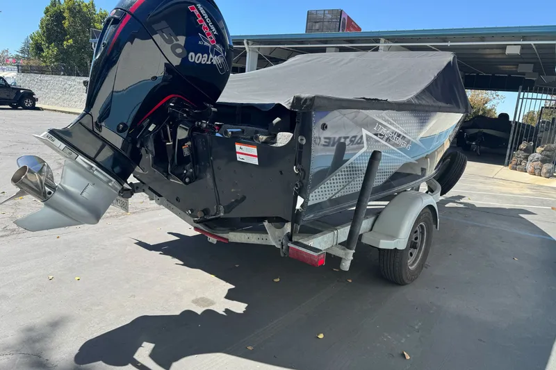 Slide: The Image of 2021 Lund 1775 Crossover XS boat on trailer with covered motor, parked outdoors. - 18