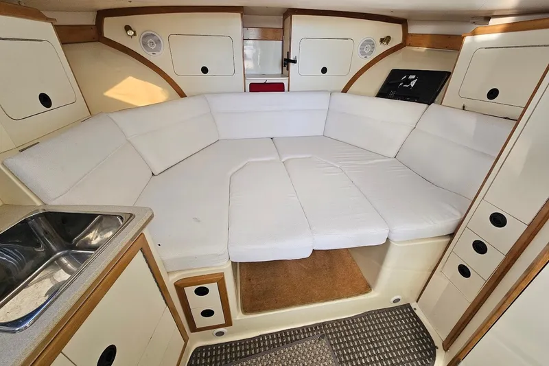 Slide: The Image of Interior of 2000 Albin 31 Tournament Express with white cushioned seating and compact kitchenette. - 19