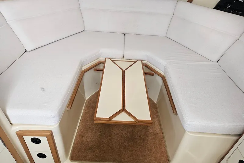 Slide: The Image of Interior of 2000 Albin 31 Tournament Express with white cushioned seating and wooden table. - 16
