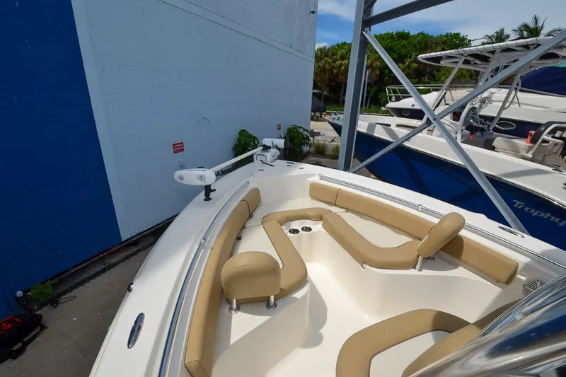 Slide: The Image of A 2018 Key West 219 FS boat with beige upholstery in the bow area, parked beside a building. - 29