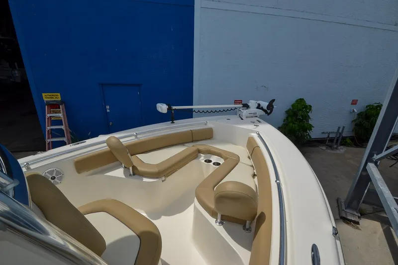 Slide: The Image of A 2018 Key West 219 FS with beige seating and a white hull, parked beside a blue building. - 19