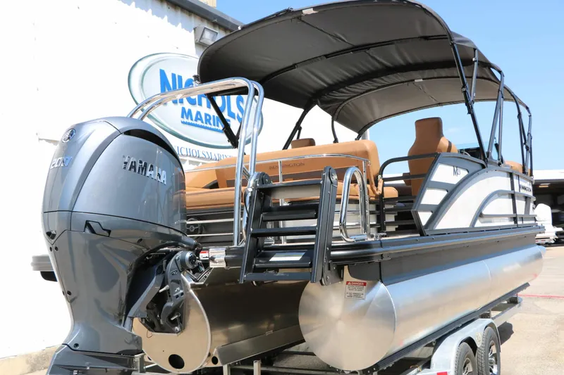 Slide: The Image of A Bennington 23 MSB pontoon boat with Yamaha engine, parked on a trailer in front of a building. - 14