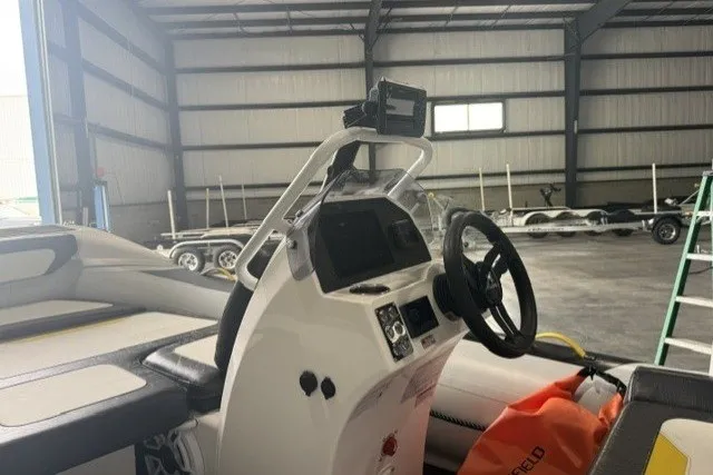 Slide: The Image of 2025 Highfield Velox 420 boat interior with steering wheel and control panel in a warehouse. - 9